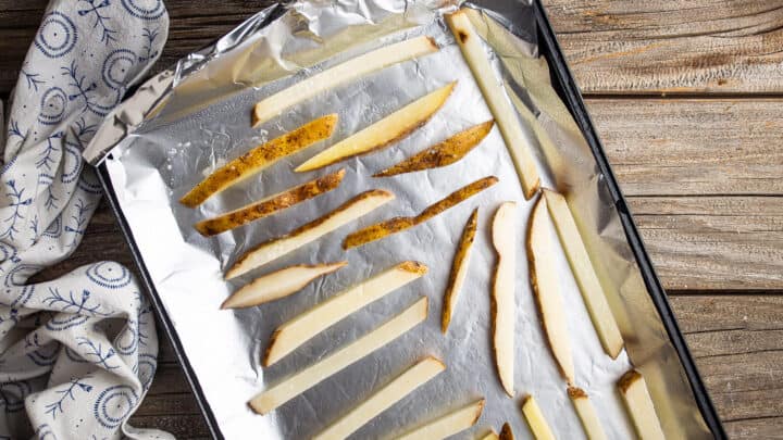 Tagliare le patatine fritte disposte in uno strato uniforme su una teglia calda.
