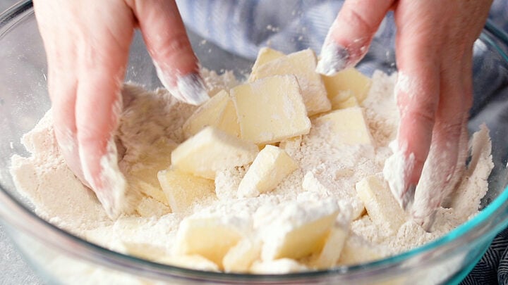 Tossing sliced butter in the dry ingredients to coat.