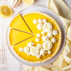 Overhead image of a sliced lemon tart with whipped cream rosettes.
