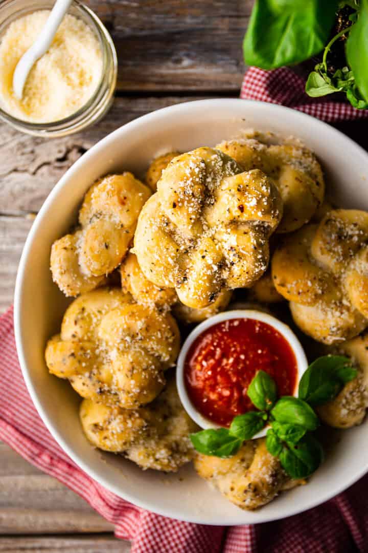 Garlic knot recipe, baked and served in a bowl with fresh basil.
