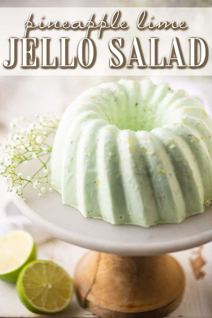 Jello salad presented on a pedestal with fresh lime and baby's breath.