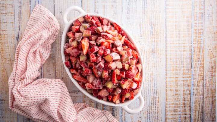 Unbaked strawberry rhubarb crisp filling in an oval baking dish.