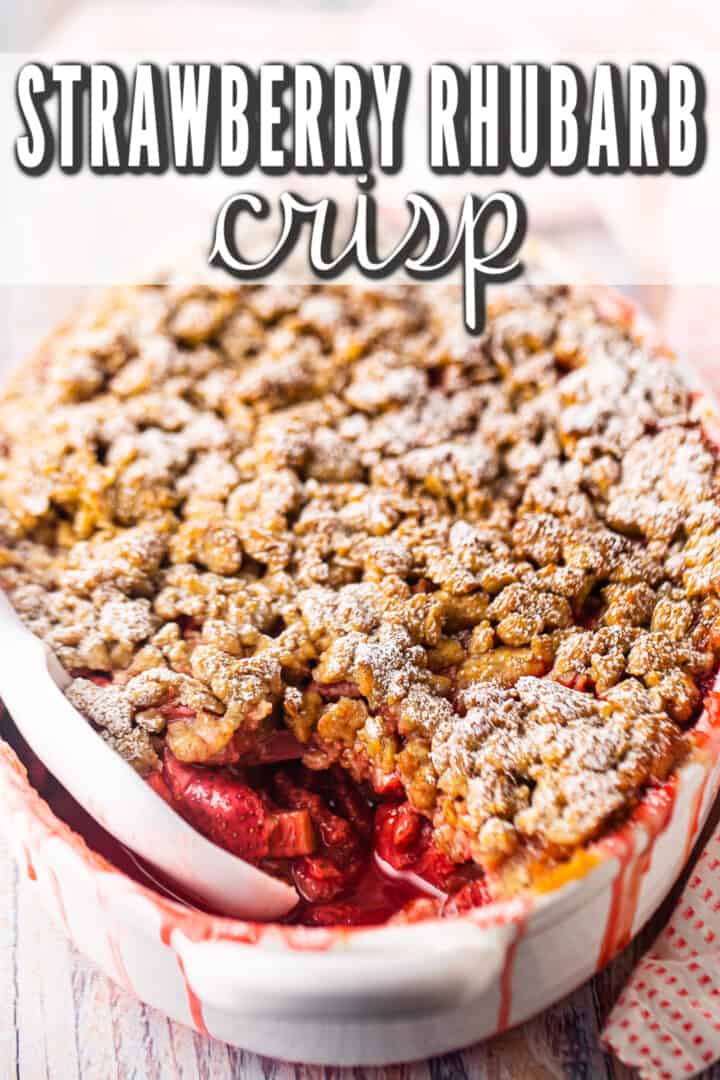 Rhubarb strawberry crisp baked in an oval dish and presented on a white tabletop.