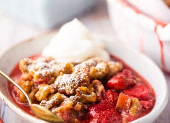 Strawberry rhubarb crisp served in a shallow bowl with whipped cream.