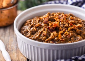 Baked beans served in a casserole dish and topped with bacon.