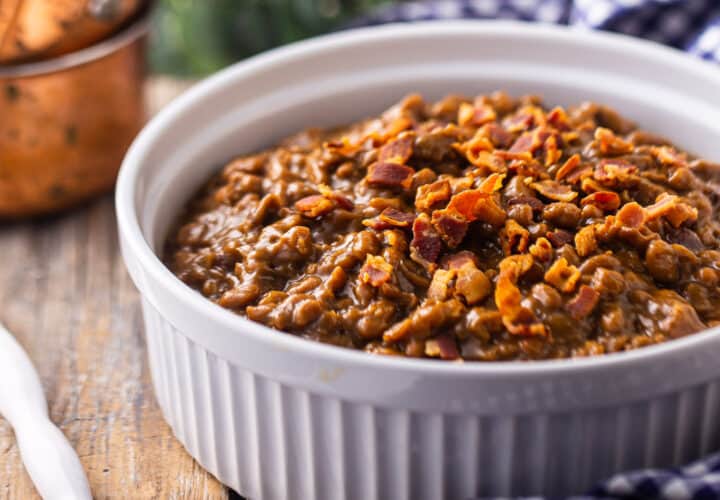 Baked beans served in a casserole dish and topped with bacon.