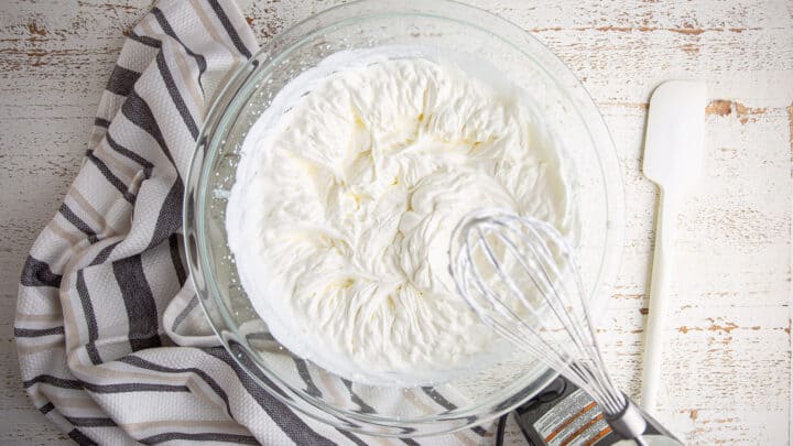 Whipped cream in a large glass mixing bowl.