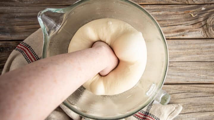 Punching down risen pretzel bun dough.