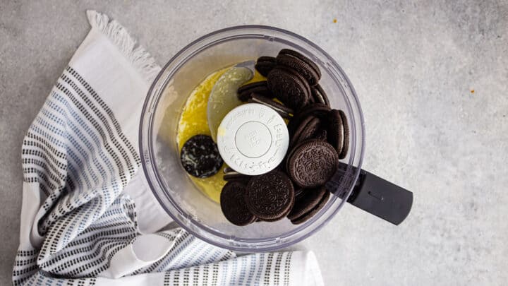 Oreos and melted butter in the bowl of a food processor.