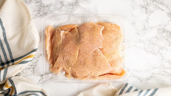 Seasoning thin sliced chicken breasts.