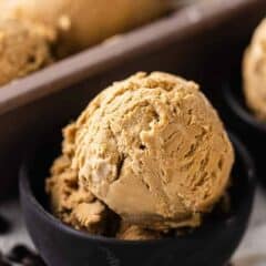 Two small bowls of coffee icecream next to a loaf pan filled with scoops of homemade coffee ice cream.