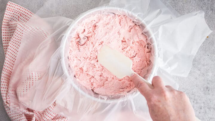 Pressing strawberry ice cream into a cake pan.