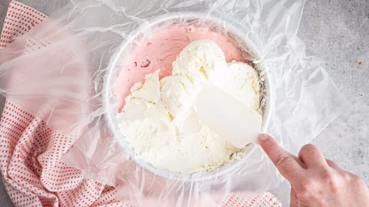 Layering vanilla ice cream over strawberry ice cream.