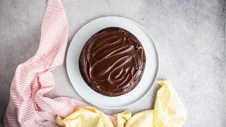 Hot fudge sauce spread in an even layer over chocolate cake.