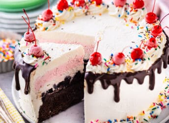 Homemade ice cream cake with layers of cake, fudge, cookies, ice cream, and whipped cream.