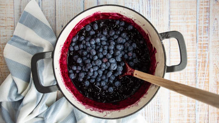 Adding fresh blueberries to blueberry crisp filling.