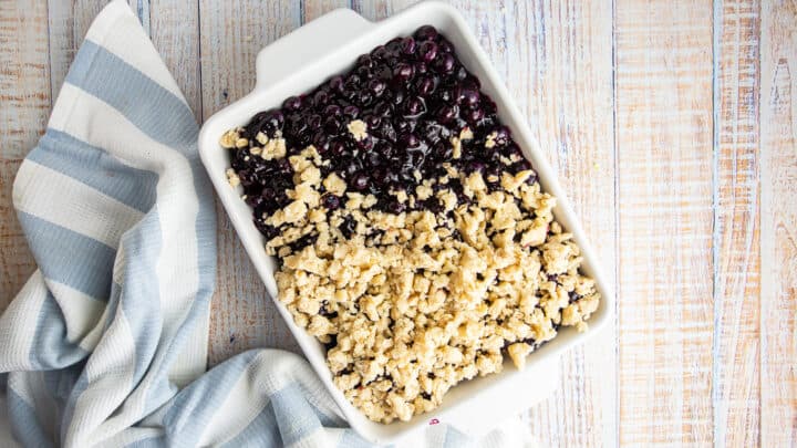 Topping unbaked blueberry crisp with crumb topping.
