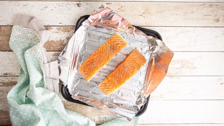 Seasoned salmon filets on a foil-lined baking sheet.