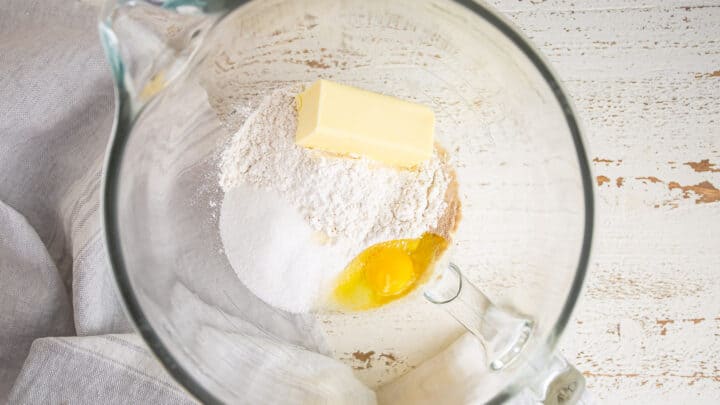 Adding flour, butter, sugar, and egg to gooey butter cake dough.