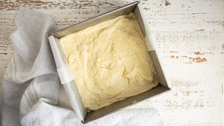 Risen gooey butter cake dough in a square pan.