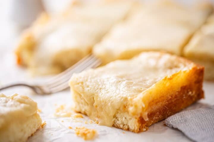 Ooey gooey butter cake recipe, cut into bars and presented on a white background.