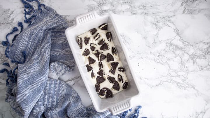 Layering cookies and ice cream into a loaf pan.