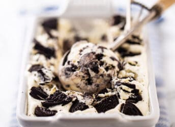 Homemade oreo ice cream in a white ceramic loaf pan with a vintage ice cream scoop.