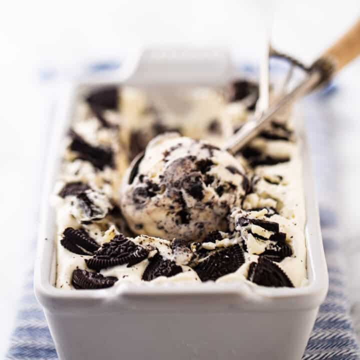 Homemade oreo ice cream in a white ceramic loaf pan with a vintage ice cream scoop.