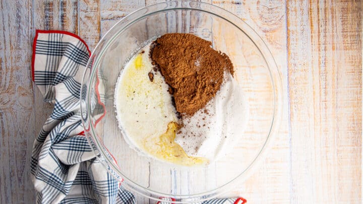 Sugar, butter, and cocoa powder in a large glass mixing bowl.