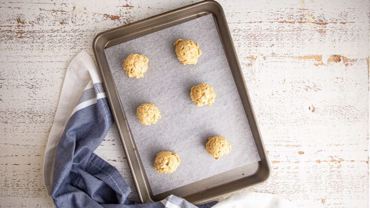 Unbaked peanut butter oatmeal cookies on a parchment-lined baking sheet.