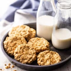 Peanut butter oatmeal cookies displayed in a vintage cake pan with bottles of milk.