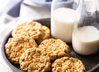 Peanut butter oatmeal cookies displayed in a vintage cake pan with bottles of milk.