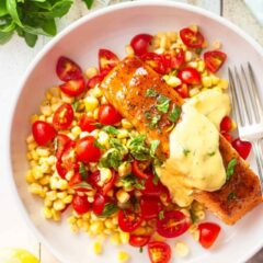 Glazed salmon in a shallow bowl with sweet corn, tomatoes, and fresh basil.