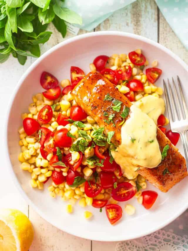 Glazed salmon in a shallow bowl with sweet corn, tomatoes, and fresh basil.