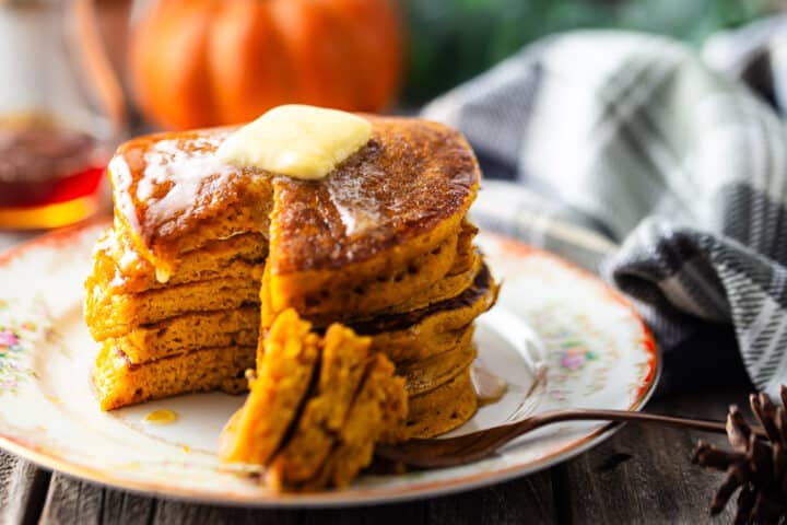 Pumpkin spice pancakes with a bite taken out to display the fluffy texture.