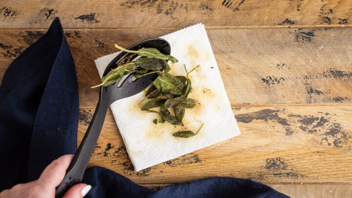 Draining fried sage leaves on paper towels.