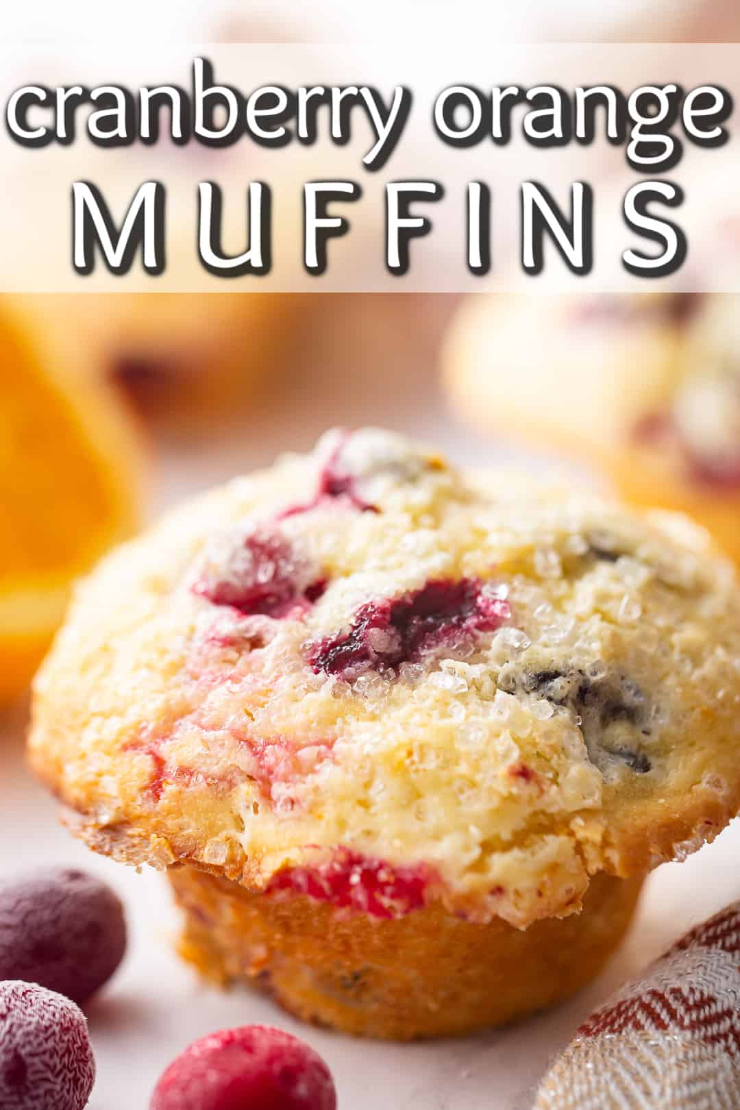 Orange cranberry muffins  with a text banner and fresh oranges and cranberries in the background.
