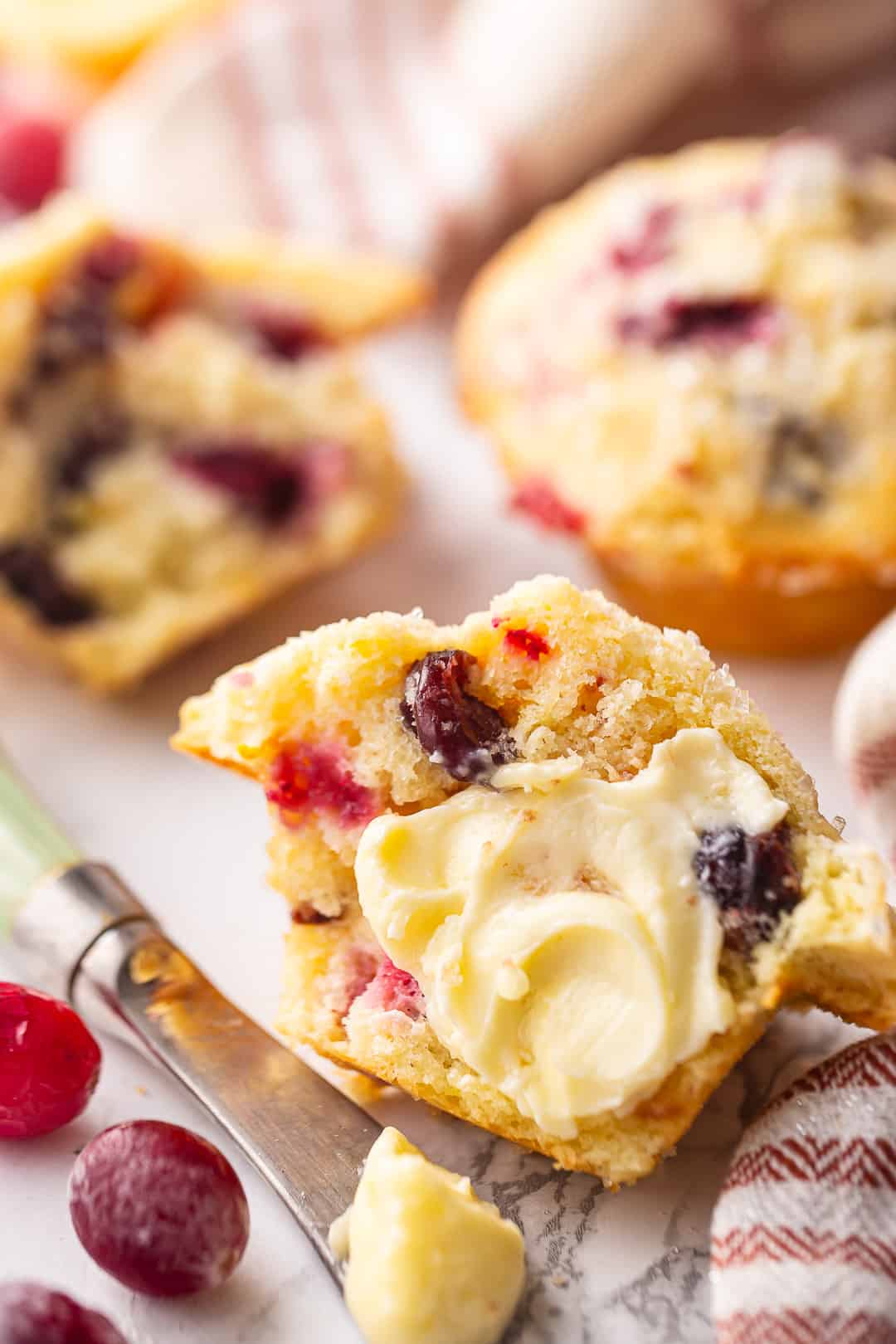 Cranberry orange muffin recipe, baked, split, and slathered with soft butter.