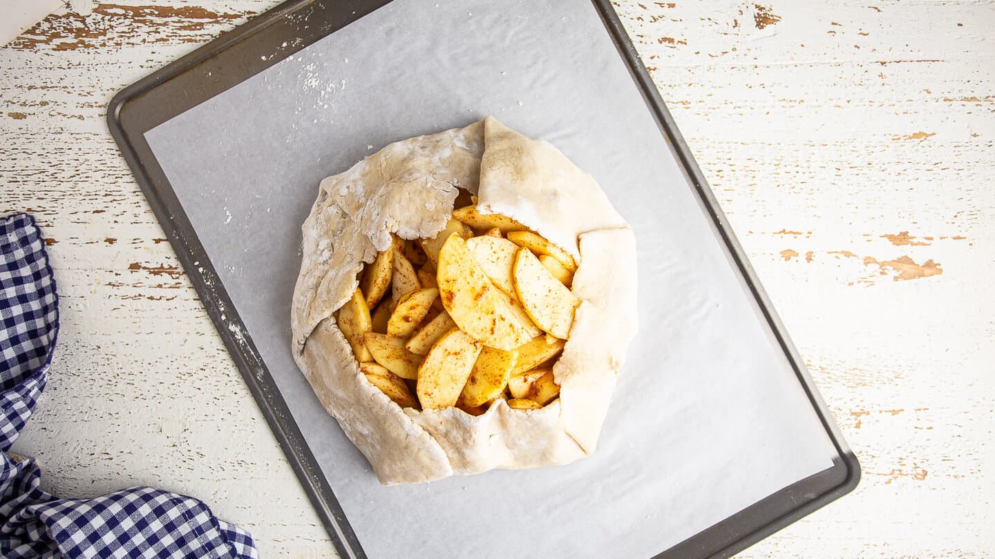 Unbaked apple galette, on a parchment-lined baking sheet.
