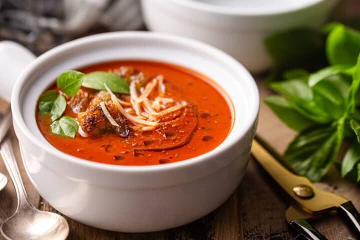 How to make tomato soup served in white crockery with fresh basil and homemade croutons.