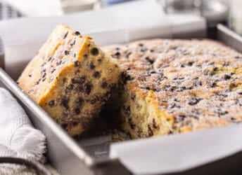 Chocolate chip cake baked in a square pan with powdered sugar on top.