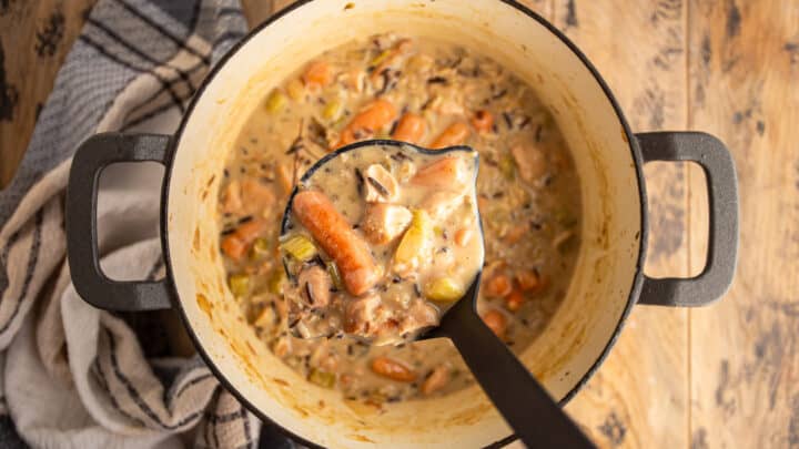 Ladling creamy chicken and wild rice soup from the pot.