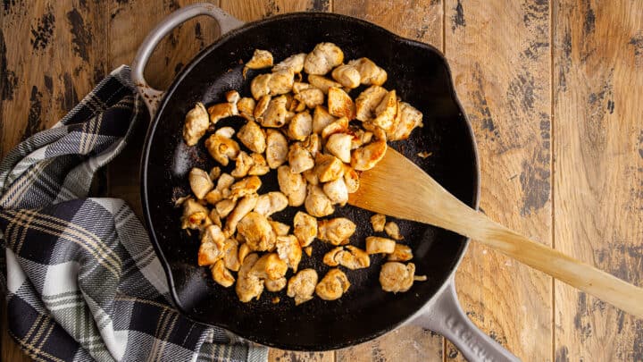 Cooking chicken until golden brown in a large skillet with salt, pepper, and garlic powder.