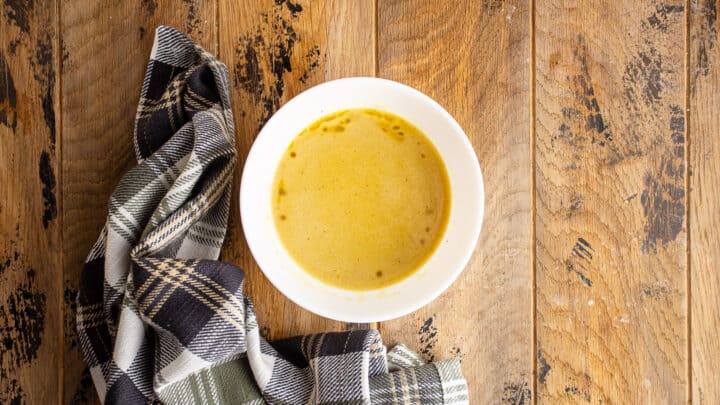 Apple cider vinaigrette in a small bowl with a plaid cloth.