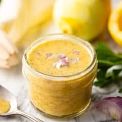 Homemade lemon vinaigrette, presented in a small glass jar and adorned with chopped shallots.