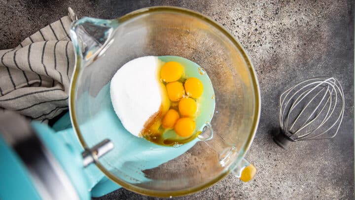 Eggs, sugar, and vanilla extract in the bowl of a stand mixer.