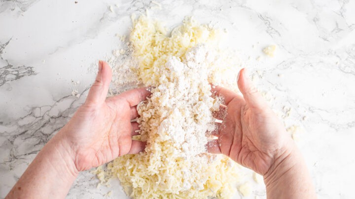 Tossing riced potatoes with flour.