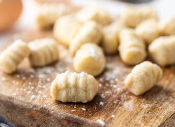 Homemade gnocchi on a wooden board with a sprinkling of flour.