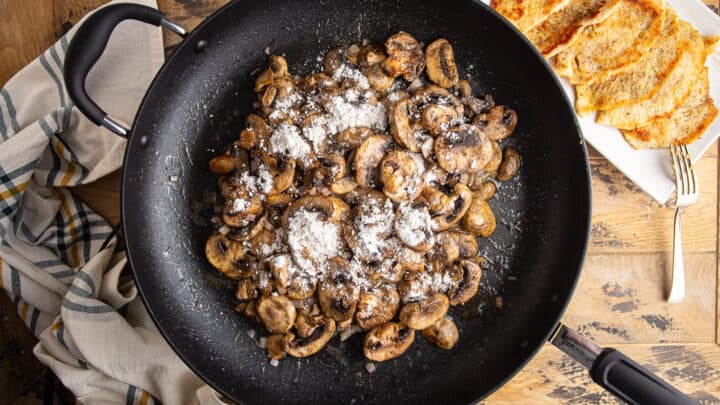 Sprinkling flour over mushrooms and shallots to make a roux.