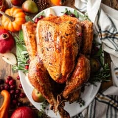 Maple sage brown butter turkey on a platter with seasonal fruits surrounding it.
